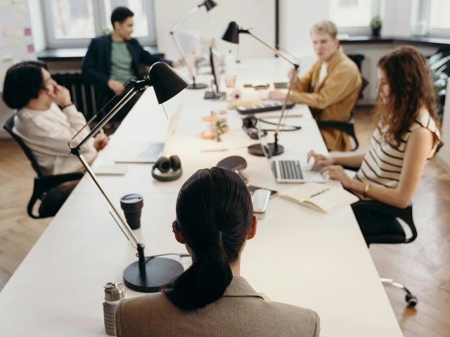 Friendly English instructor leading a corporate meeting for a Japanese company.