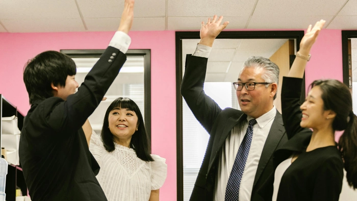 Japanese professionals celebrating success with a high-five during an English group lesson.